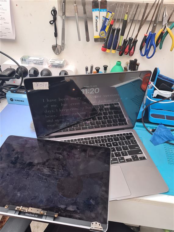 iPhone 14 Pro screen replacement next to an open MacBook Air