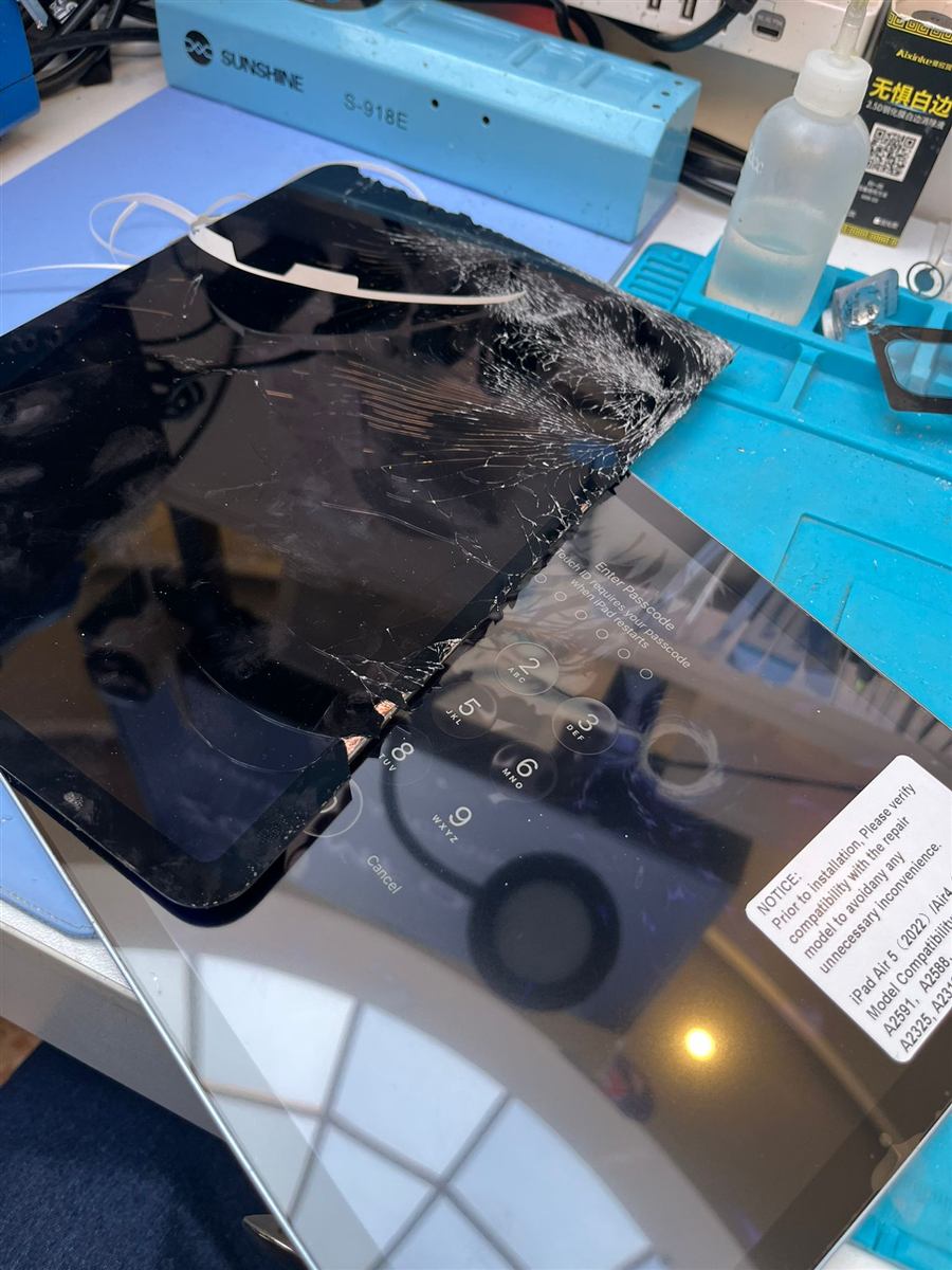 Shattered iPad Air screen lifted away next to the new replacement screen on the CCFix bench
