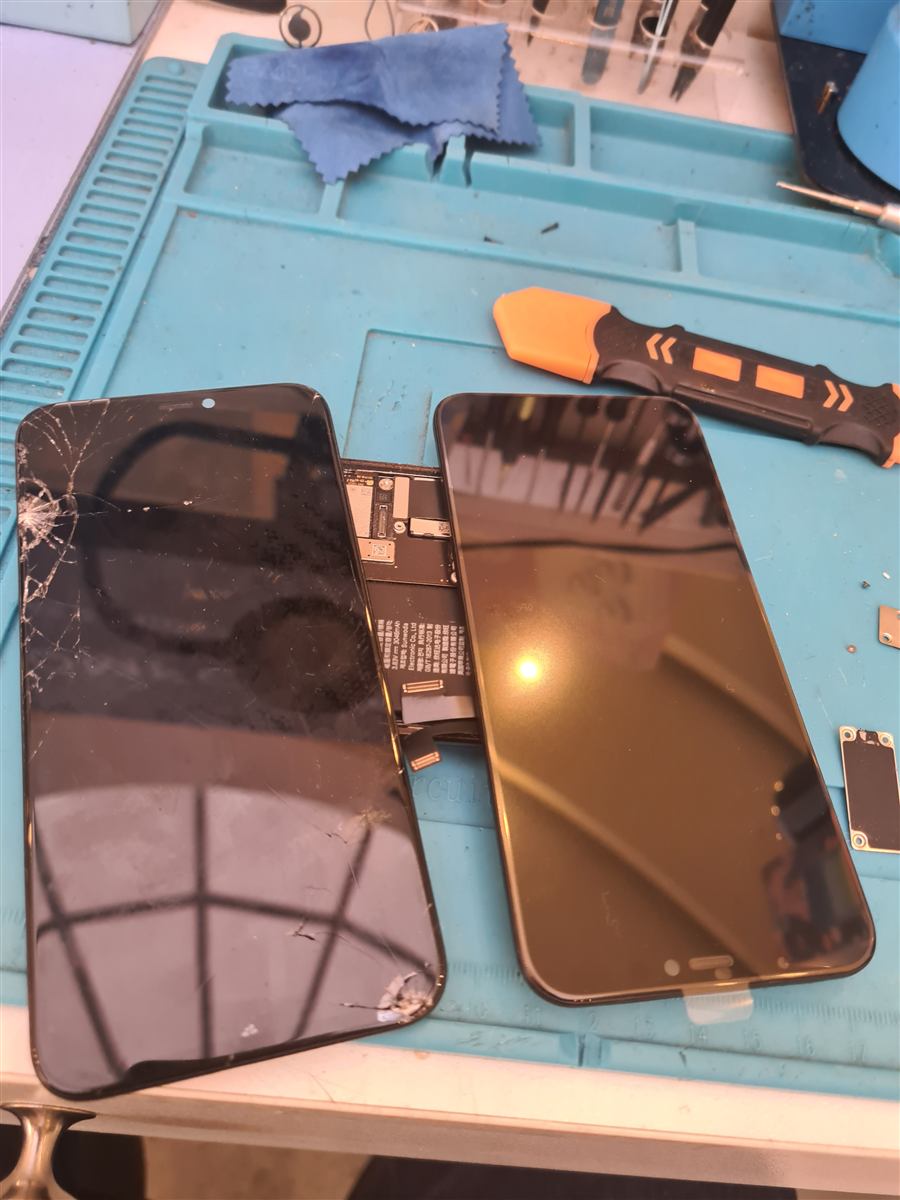 Cracked iPhone 11 Pro screen next to its new replacement display on the CCFix bench