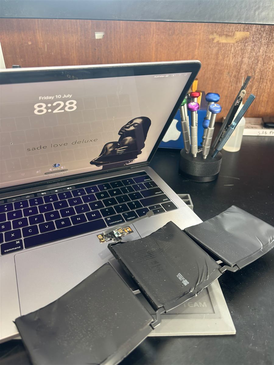 MacBook Pro on the CCFix bench with its swollen battery cells removed and laid in front